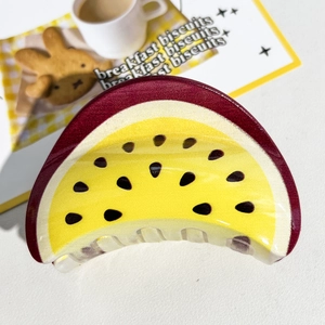 Détail d'une pince à cheveux en forme de fruit de la passion rouge et jaune élégante
