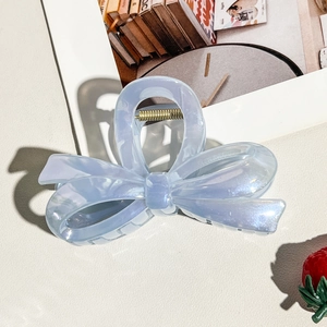 Macro detail of jelly blue bow hair claw with pearlescent finish and gold spring