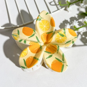Detail view of tropical plumeria hair claw clip with fresh orange and leaf UV print