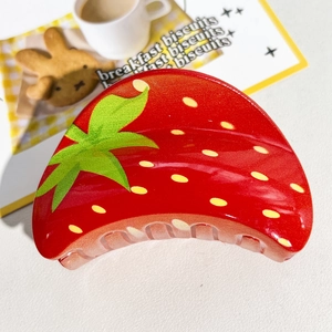 Gros plan détaillé d'une pince à cheveux brillante en forme de fraise rouge éclatante