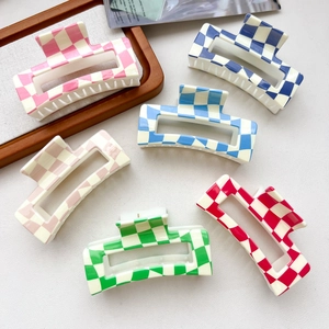 Six colorful checkered hair claws in pink blue green and red on a white textured background