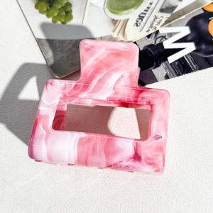 Macro detail of pink and white marble texture hair claw clip made of acetic acid sheet