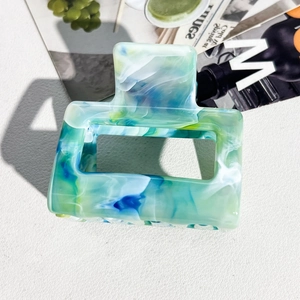 Macro shot of rectangular acetate hair claw clip with green and blue marble texture finish