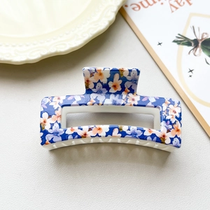Detail of blue floral checkered hair claw clip with orange accents on a vintage tray