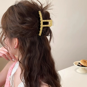 Elegant cream shark hair claw with red polka dots worn on long wavy hair in a home setting