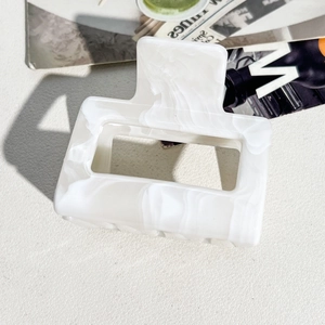 Macro shot of 5cm rectangle hair claw clip with white marble texture and hollow frame design