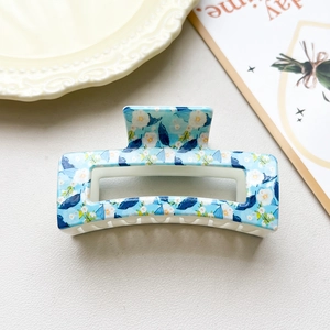 Close-up of light blue floral checkerboard hair claw clip with cutout rectangular design