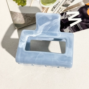 Detail of light blue marble textured acetate claw clip with a glossy modern finish