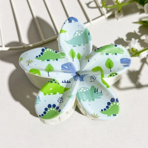 Detail shot of a light blue plumeria hair claw clip featuring cute cartoon dinosaur prints