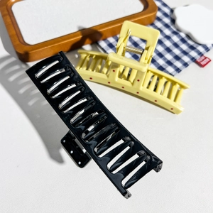 Close-up of large rectangular hair claws with strong metal springs in black and yellow