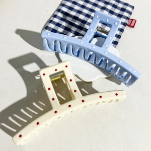 Close-up of large hair claw clips in blue and beige with chic colorful polka dot pattern