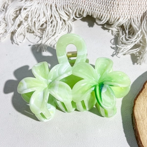 Detail view of light green flower hair claw clip with marble texture and gold metal spring