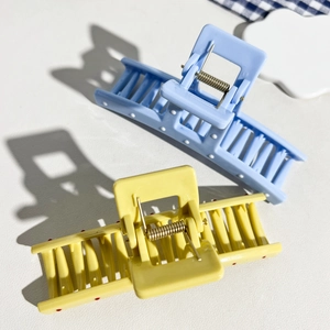 Detail view of large pastel blue and yellow hair claw clips with multi-tooth structure
