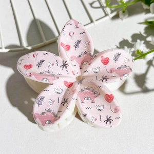 Detailed macro view of large pink flower claw clip with colorful cartoon dinosaur patterns