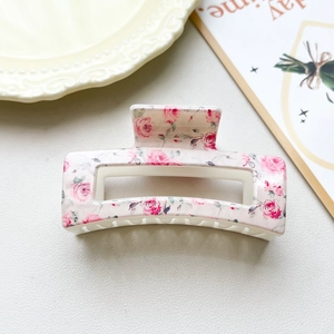Close-up of a cream hair claw clip with delicate pink rose floral patterns in a vintage style