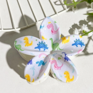 Detailed view of white floral hair claw clip featuring colorful cartoon dinosaur prints