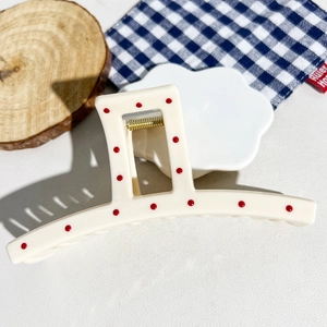 Close-up of cream square hair claw clip with red polka dots and gold metal spring