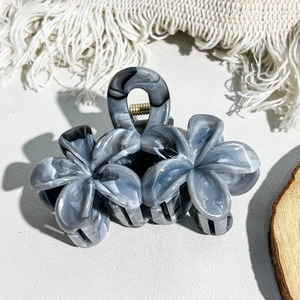 Detail view of marble pattern hair claw clip with floral design and gold metal spring