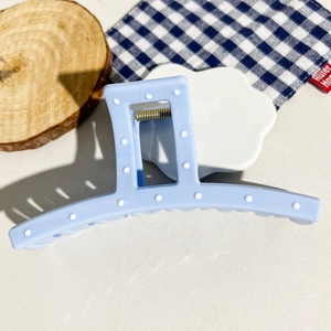 Detail of light blue square hair claw clip with 3D white dots and gold spring on desk