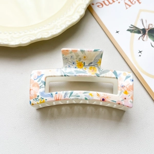 Detailed view of an 8.5cm floral claw clip with vintage orange and blue flower patterns