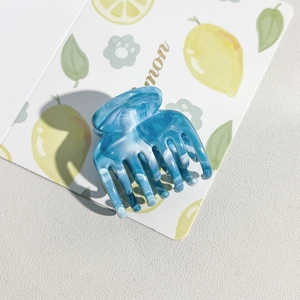 Macro detail of blue marble textured hair claw clip with seven teeth on lemon card