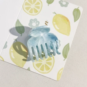Close-up of blue marble hair claw clip with acetate finish on lemon motif background
