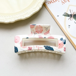 Detail of checkered hair claw clip with pink floral pattern on creamy white finish