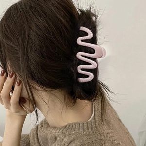 Pince à cheveux rose ondulée avec couture blanche portée sur cheveux foncés