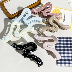Détail de pinces à cheveux en forme de S multicolores avec motifs de cœurs et nœuds