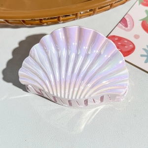 Detailed view of a seashell-shaped hair claw clip with iridescent pearlescent finish