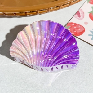 Macro shot of seashell hair claw with holographic gradient pink to purple metallic finish
