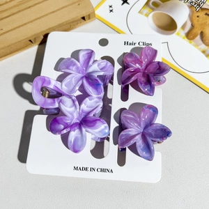 Détail de quatre pinces à cheveux florales en acétate violet sur carte de présentation