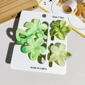 Détail de quatre pinces à cheveux fleurs en résine marbrée verte sur carte de vente