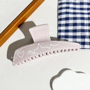 Vue détaillée d'une pince à cheveux rose avec motif cœur et design ondulé élégant