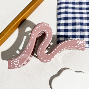 Vue détaillée d'une pince à cheveux vague mauve avec motifs cœurs et nœuds
