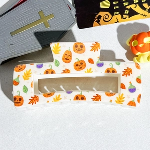 Detail view of square Halloween hair claw with pumpkin and maple leaf UV printing