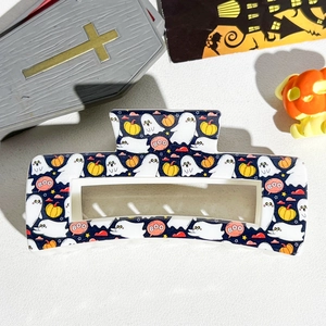 Detail of Halloween hair claw clip with ghost and pumpkin patterns on dark blue resin