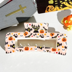 Detailed view of pink Halloween hair claw clip with festive pumpkin and ghost prints
