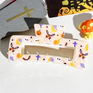 Macro detail of Halloween 8.5cm square hair claw with festive pumpkin and skull patterns