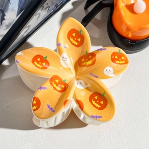 Detail of Halloween flower hair claw with pumpkin, ghost and bat patterns on orange surface