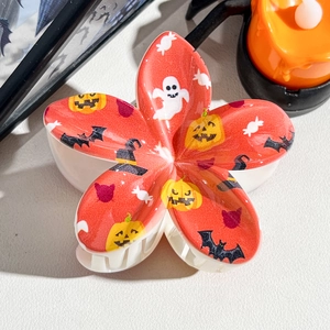 Close-up of flower-shaped Halloween claw clip with ghosts and pumpkin prints
