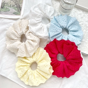 Detailed macro view of five lace scrunchies in various colors on textured fabric
