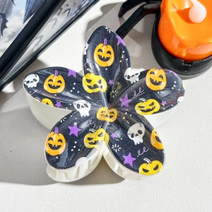 Detail view of flower-shaped Halloween hair claw with pumpkin and skull prints