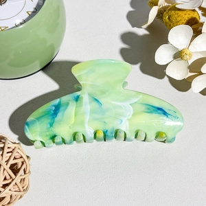 Detailed close-up of marble pattern hair claw clip with green blue and yellow swirls
