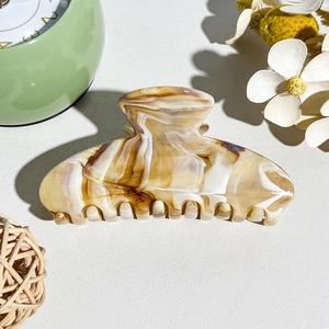Macro detail of the smooth marble texture and polished teeth on the large hair claw clip