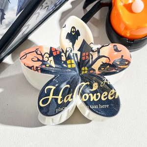 Detailed close-up of a Halloween themed floral hair claw with pumpkin and ghost patterns