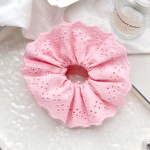 Macro shot of pink lace scrunchie with floral embroidery on rippled glass background