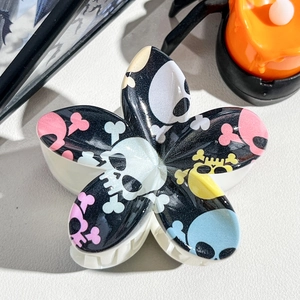 Detail view of flower-shaped hair claw with Halloween skull pattern on white background
