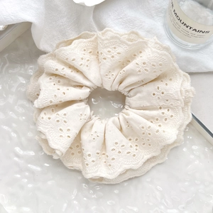 Detail of off-white lace scrunchie featuring intricate eyelet embroidery and layered ruffles
