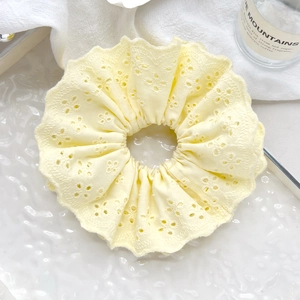 Close-up of cream yellow lace scrunchie with delicate floral broderie anglaise embroidery